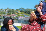 Refugess enjoying food in the sun in New Zealand